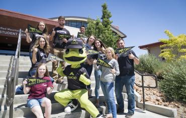 Mascot Wizard the Lizard with students on the steps of the Red Mountain Building