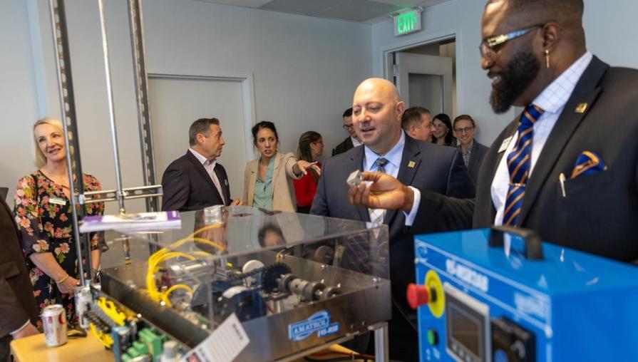 TMCC's Mike Peyerl and Dr. Ayodele Akinola inspect parts of a cutting-edge machine among colleagues.