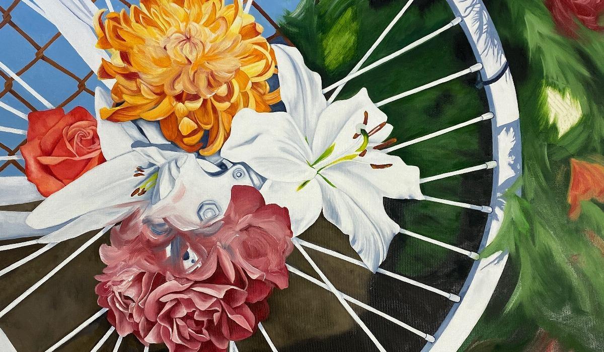 A painting of a white bicycle with red, yellow, and pink flowers in its wheel rests next to a green bush.