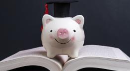 Piggy bank with a mortarboard sitting on top of an open book.