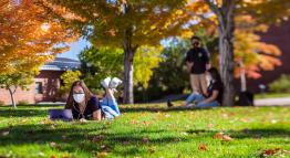 Students sitting outdoors on the grass.
