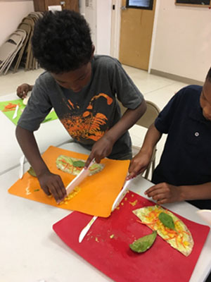 Children making a veggie wrap.