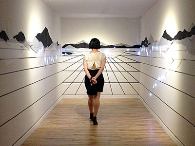 Photograph of woman standing in a small art gallery