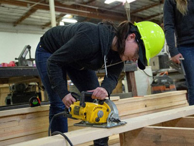 Woman in hard hat using a power saw.