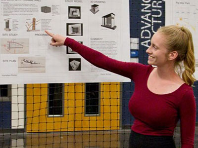 Smiling student gesturing to a project diagram.