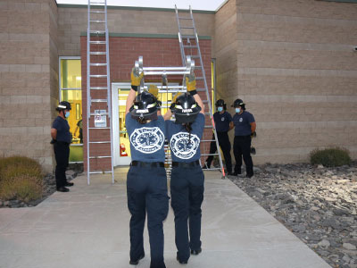 Students raise ladders together at the fire academy.