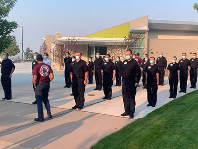 Students in uniforms and masks line up outdoors.