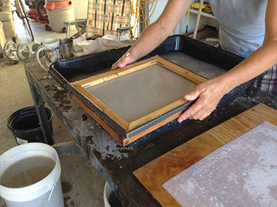 A screen on a wooden frame with wet pulp on it.