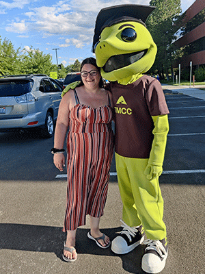 Student Amber Moore standing next to TMCC mascot Wizard the Lizard.
