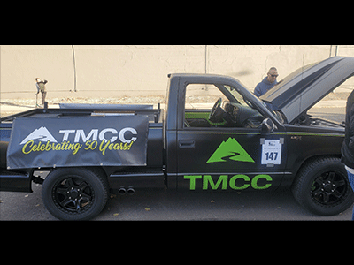 Black truck with green decals showing the TMCC logo.