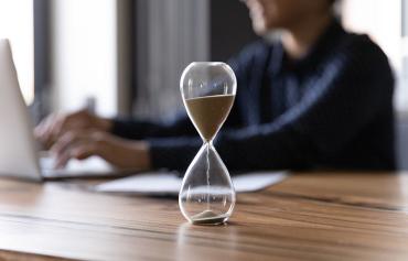 Hourglass with person on computer.