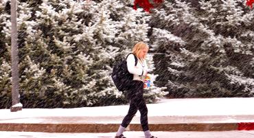 Student walking through campus on a snowy day.