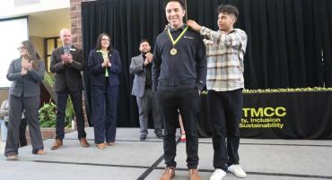 Young man places medallion around brother's neck during Unity Graduation Celebration.