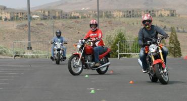 Students riding motorcycles in parking lot early learning environment.