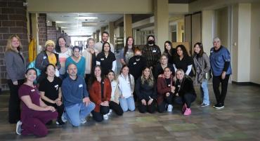 A group photo of dietetic technician, dental hygiene, and social work students with their instructors in the hallway outside Café Verde.