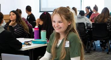 A nursing student smiles in class alongside several of her peers.