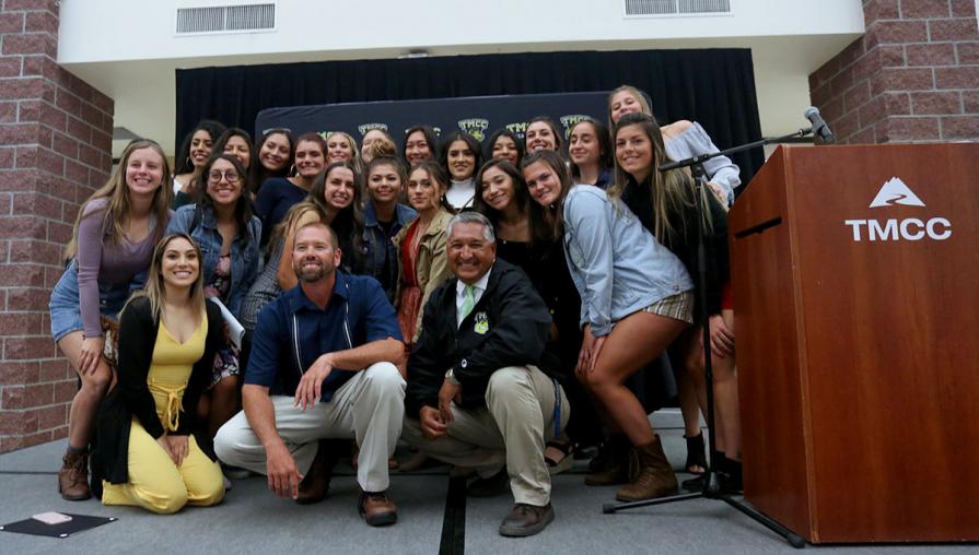 Women's soccer team posing with their coaches.