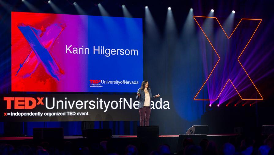 Dr. Karin Hilgersom speaking on stage in front of the TedX screen.