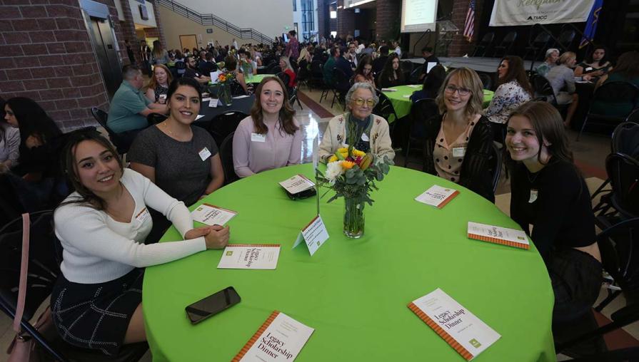 Donor Jean Myles with scholarship recipients sitting at a table.