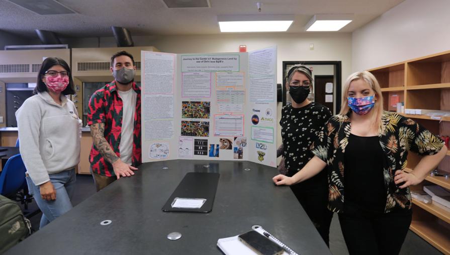 Students pose by research posterboard.