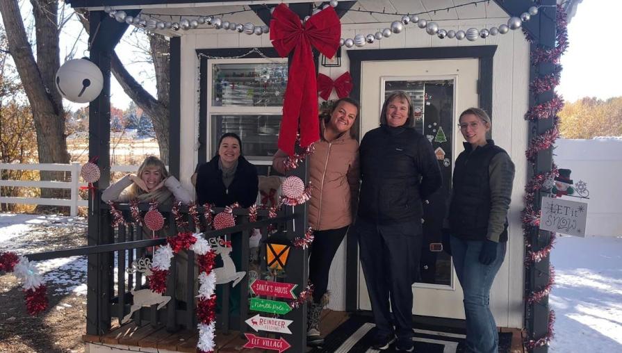 Julie McMahon and vet nursing students beside a Santa Paws holiday decorated cabin.