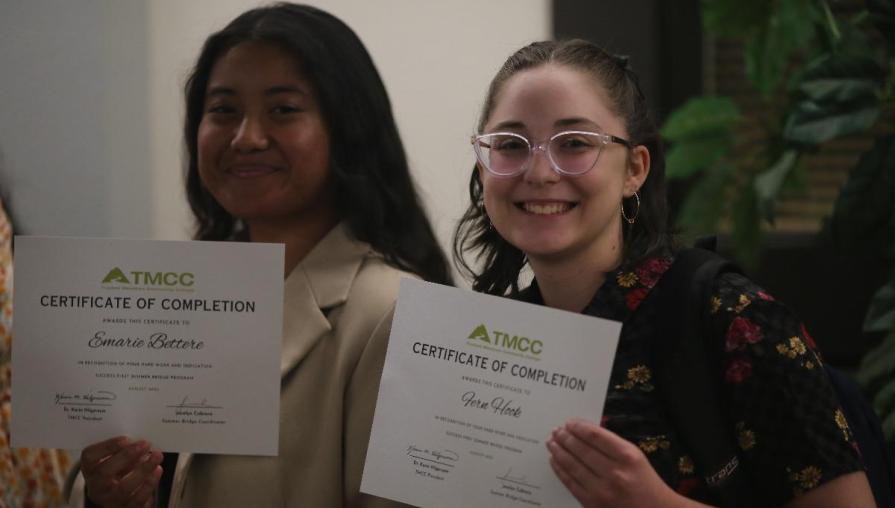 Students smile while proudly holding their certificates of completion for the Summer Bridge program.