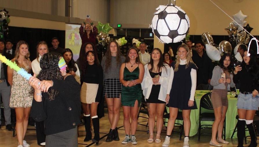 The Men's and Women's Soccer players enjoy hitting a piñata shaped like a soccer ball.