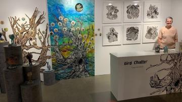 Candace Garlock stands happily beside her "Bird Chatter" exhibition inside the Reno-Sparks Convention Center.