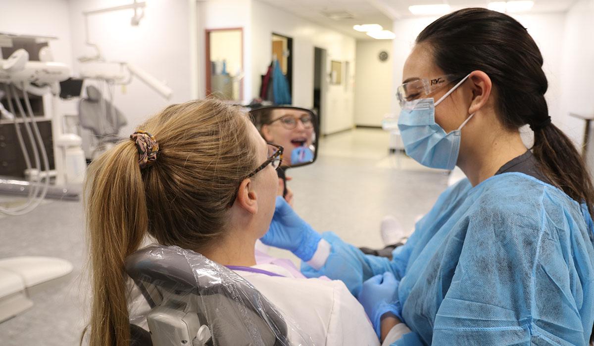 A dental hygiene student practices on a patient.