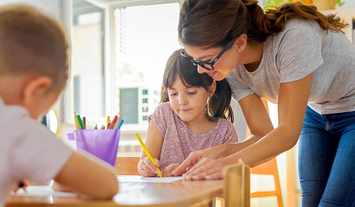 A teacher helping elementary students.