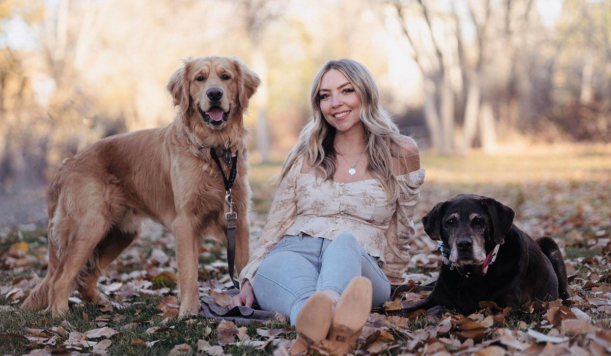 Annie Beach-Hills sits outdoors with her dogs.