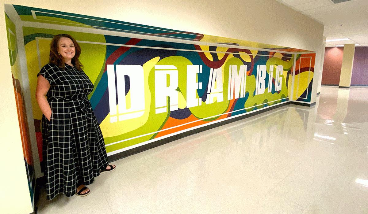 Art student Ashley Gottlieb stands next to the mural she painted in the Red Mountain building.