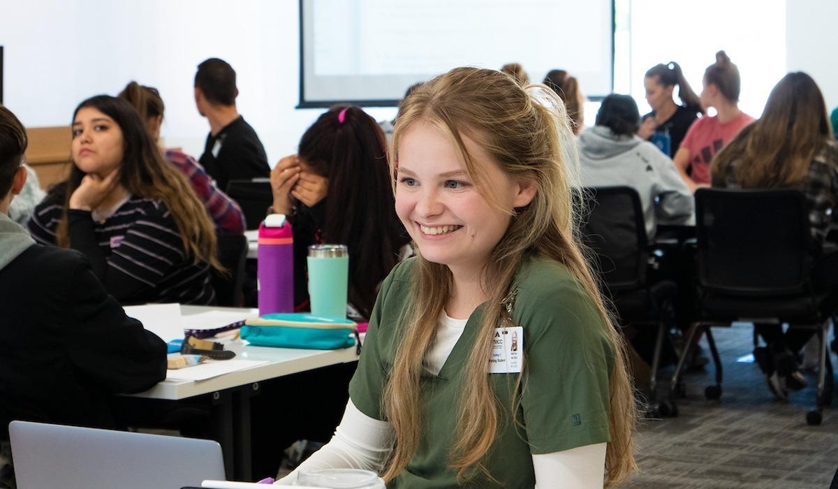 A nursing student smiles in class alongside several of her peers.