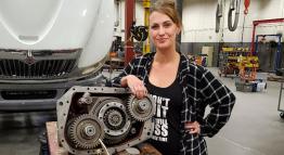 TMCC student Laurel Allen standing with an automobile engine.