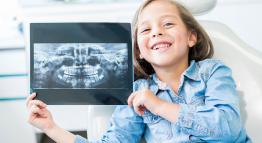 Smiling child holding a dental x-ray.