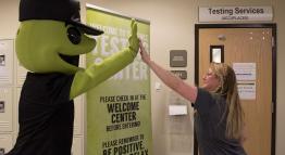 TMCC's mascot Wizard the Lizard gives a high-five to a Testing Services staff member.