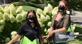 Two students wear masks while posing with SGA bags.