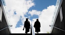 two graduates walking toward clouds