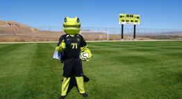 Mighty the Lizard mascot stands on the TMCC soccer field.