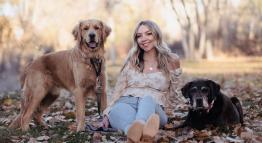 Annie Beach-Hills sits outdoors with her dogs.