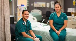 Student nurses relax by bedside in hospital setting.