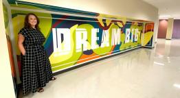 Art student Ashley Gottlieb stands next to the mural she painted in the Red Mountain building.