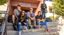 Students sit happily together on steps to Red Mountain Building.