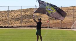 Coach flies the TMCC Mighty Lizards flag upon the soccer field.