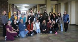 Students from the dietetic technician, dental hygiene, and social work programs pose with their instructors for a group photo in the hallway outside Café Verde.