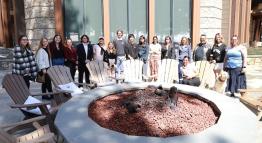 Hospitality and Tourism Management students with their instructor on a sunny day outside with a fire pit and wooden chairs in front at the Ritz-Carlton in Truckee, CA.