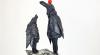 Two crows, one tall and the other short, stand atop newspaper clippings and gaze up at the sky. Terminus and Telos, by Candace Garlock.
